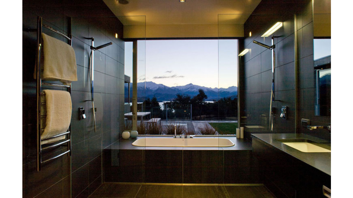 In several of his residential projects Marc Scaife has used a single sliding window system over adjoining rooms. In this wing at Release Retreat the en-suite bathroom (at left in the exterior photo) was spanned by a single panel which withdraws back over a fixed light in the main bedroom. The moving panel on the right of the bedroom also shares the same fixed light.