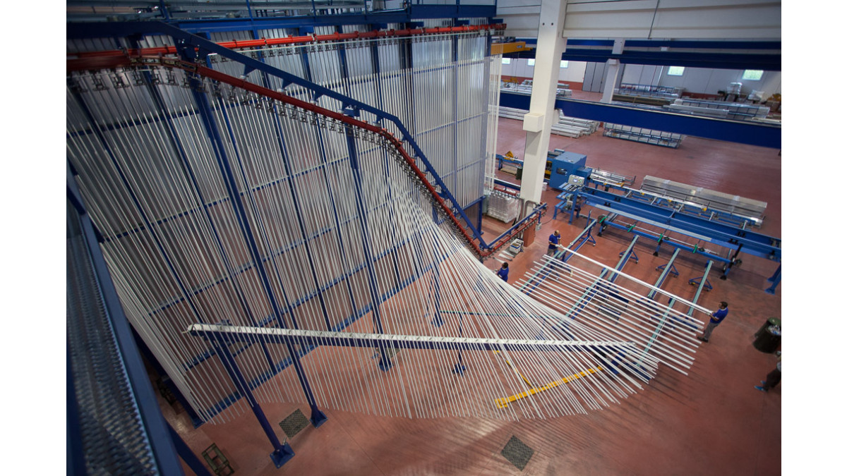 A typical vertical powder coating line with extrusions being lifted into position.