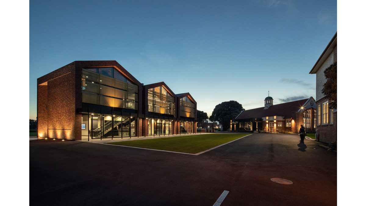 The library on right has a glazed foyer that is largely transparent when backlit at night.