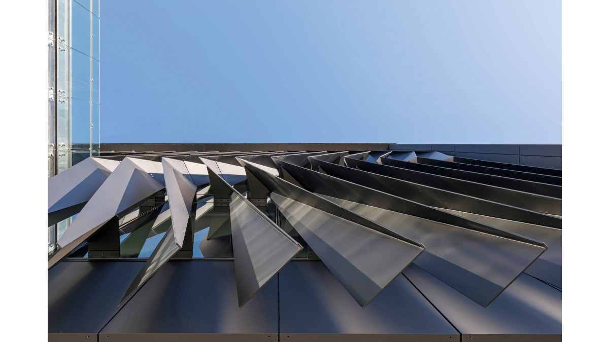 The ground view looking up at an array of geometric sun control fins on the western side of the Waikato University building.