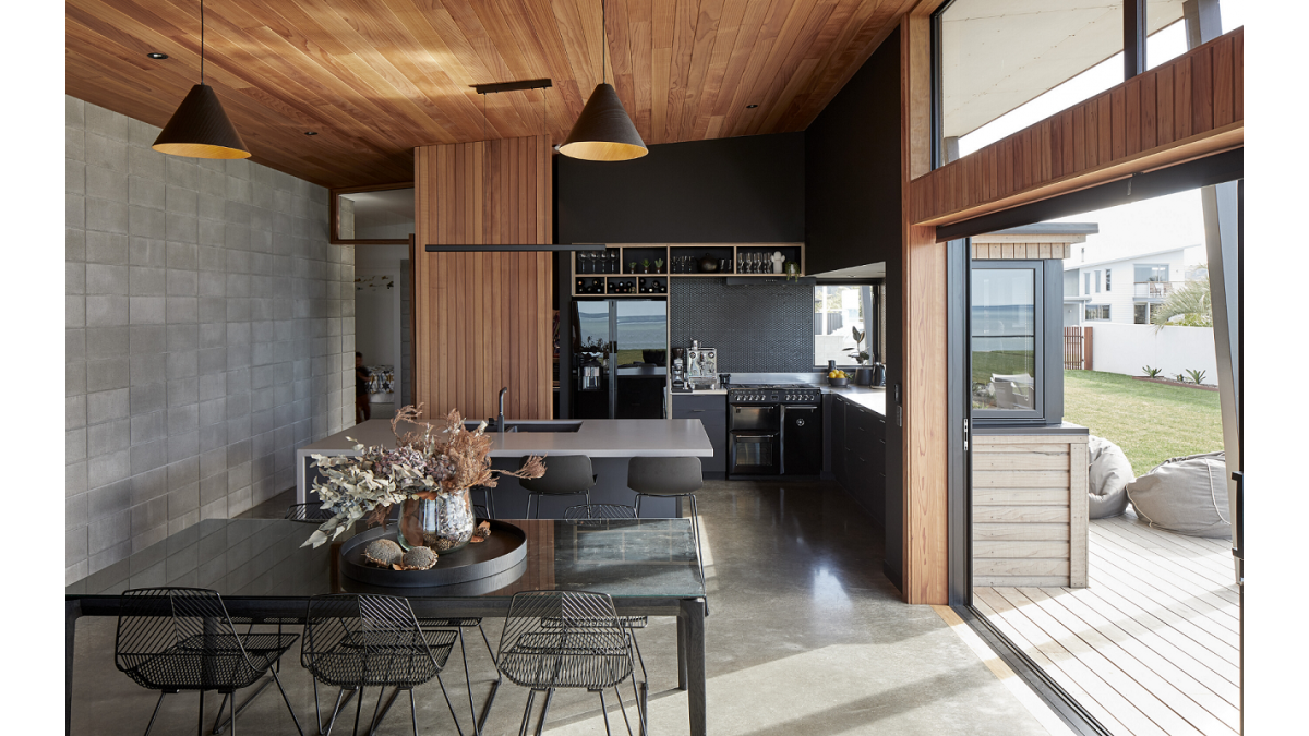 The dining area features an over-the-wall sliding door with large fixed windows above it. Sliding and casement windows let light into the black kitchen.