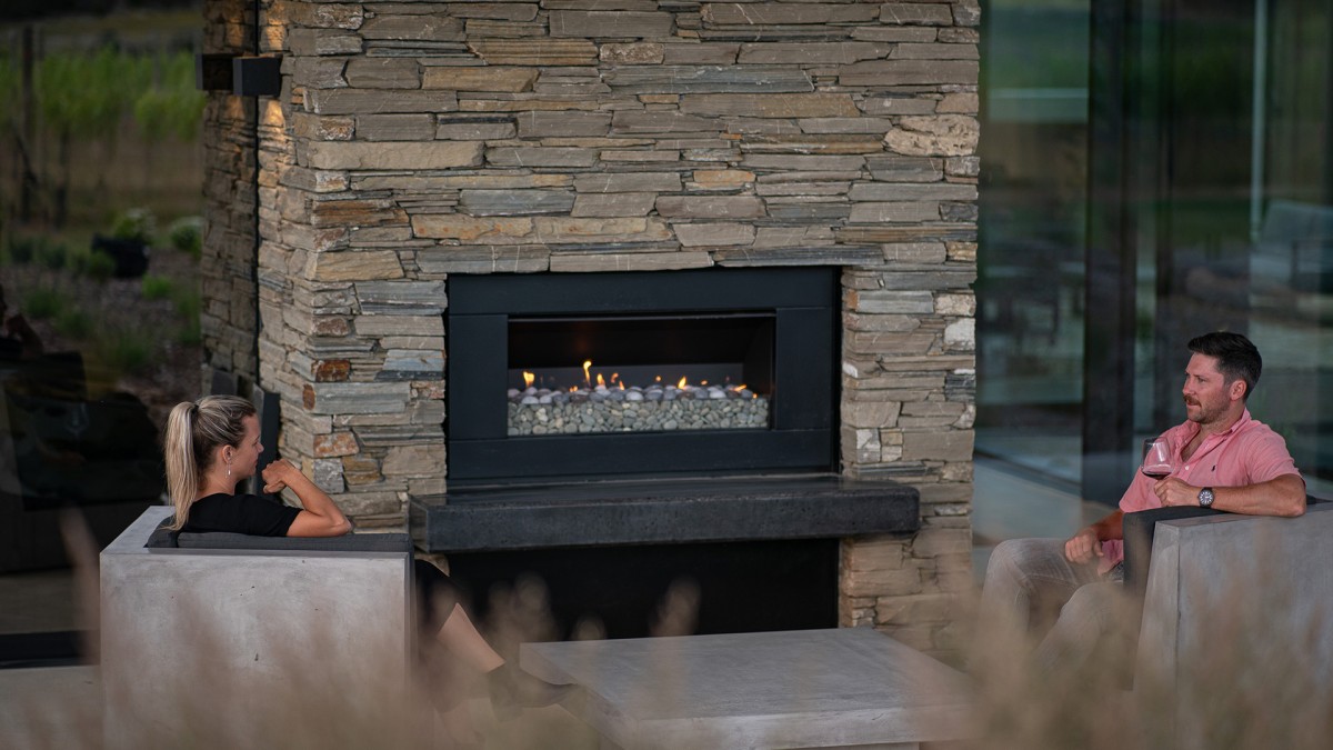 The EF5000 Outdoor Gas Fireplace is built into a schist wall at the rear of the home.