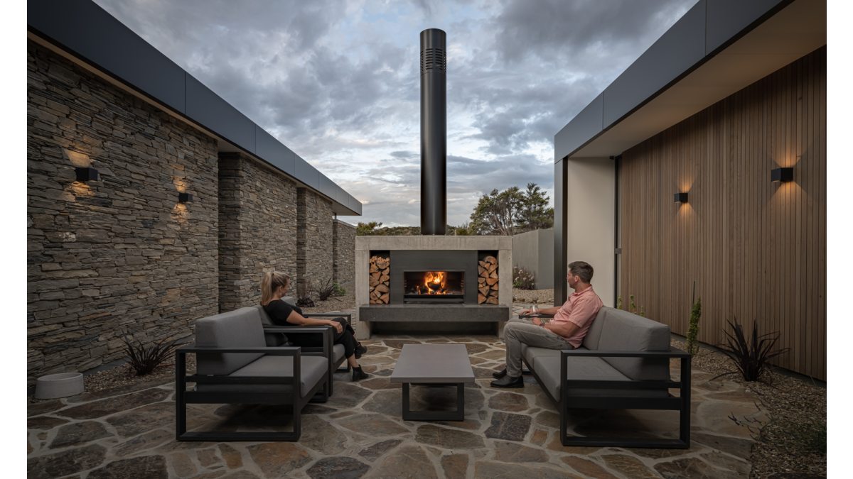 Escea’s EW5000 Outdoor Wood Fireplace serves as a central gathering point for cooking and entertaining.