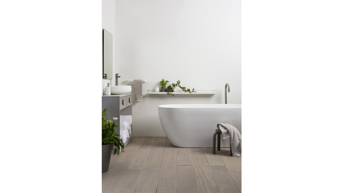 This serene bathroom features walls painted in Resene Lustacryl Kitchen and Bathroom interior semi-gloss waterborne enamel tinted to Quarter Merino and vanity in Half Stonehenge and Eighth Stonehenge. Floor in Resene Waterborne Woodsman tinted to Bleached Riverstone. Bath and basin from Athena Bathrooms, basin tap and bath filler from Voda Plumbingware. <br />
<br />
Stylist: Megan Harrison-Turner. <br />
Photography: Bryce Carleton.